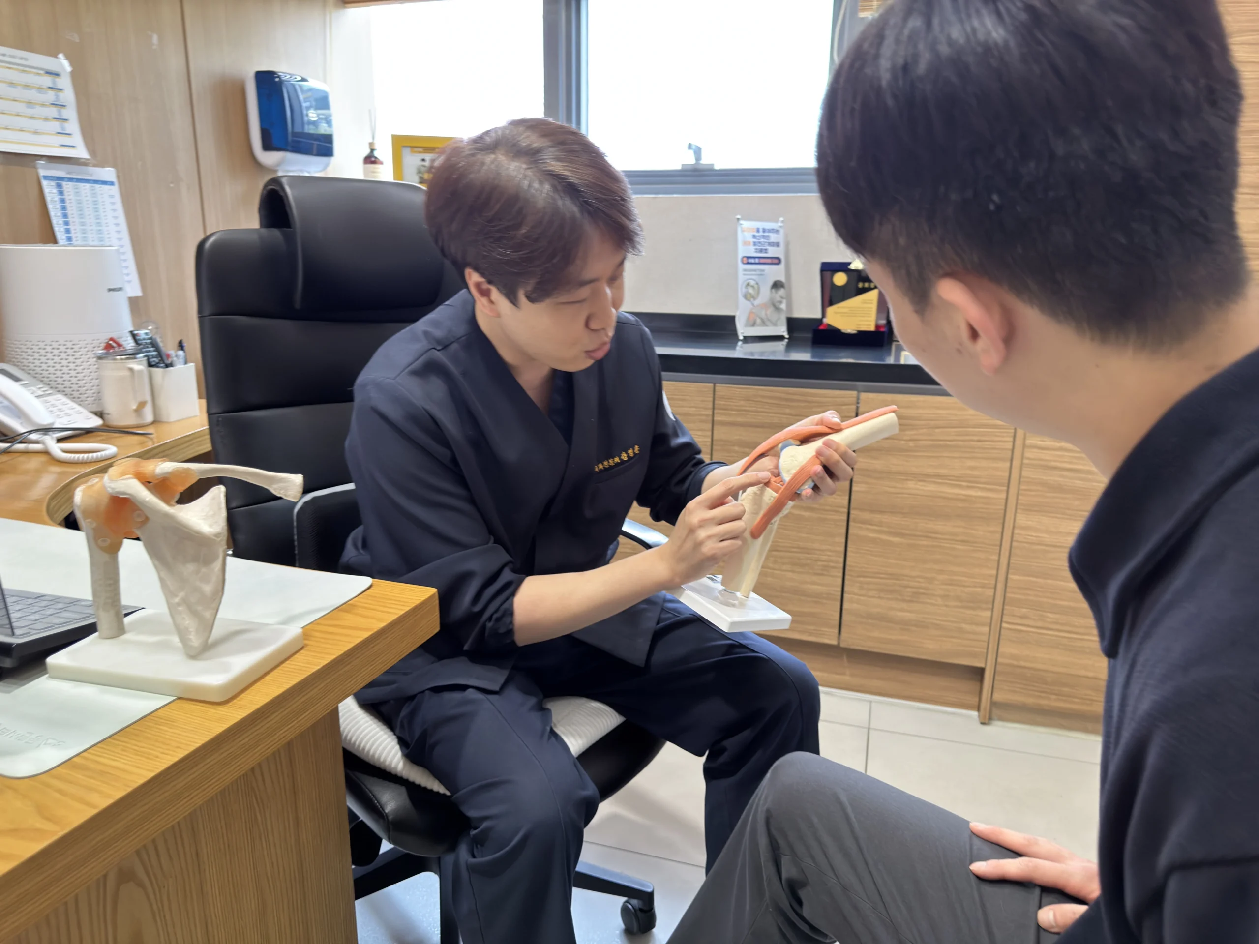 오산 충수절제술 회복기간|정형외과 전문의가 무릎 관절 모델을 활용하여 환자에게 설명하는 진료 장면